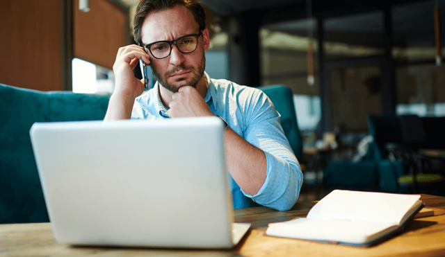 Man on phone looking at laptop