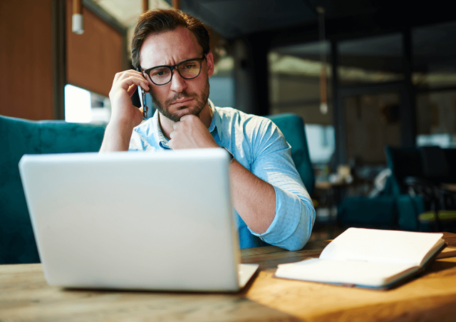 Man on phone looking at laptop